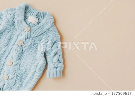 Baby knitted onesie on beige background. Fashion newborn clothes. Flat lay top view. Wool kid soft clothing. Infant trendy bodysuit made of organic eco friendly cotton. Children wardrobe. Baby garment 127569617