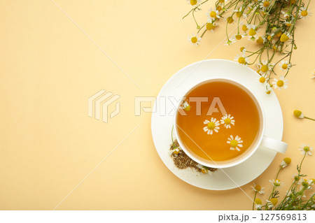Aromatic herbal tea in white cup and chamomiles on beige background. Space for text Aromatic herbal tea in white cup and chamomiles on beige background. Space for text 127569813