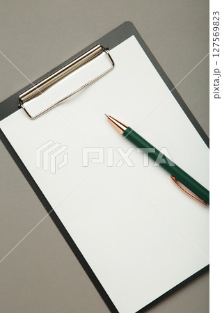 Black tablet with piece of empty paper and pen on grey background. Vertical photo Black tablet with piece of empty paper and pen on grey background. Vertical photo 127569823