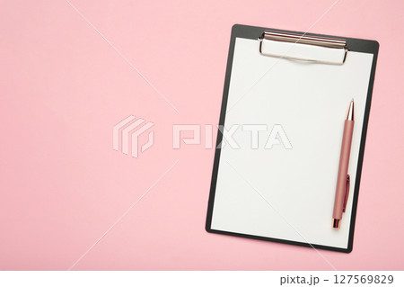 Black tablet with piece of empty paper and pen on pink background. Black tablet with piece of empty paper and pen on pink background. 127569829