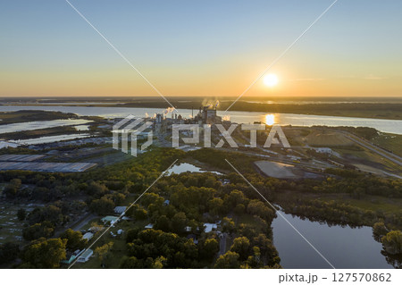 Aerial view of wood processing factory with smoke from production process polluting atmosphere at plant manufacturing yard. Industrial site at sunset 127570862