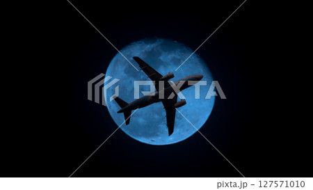 Airplane in the sky. Airplane in flight at sunset or evening sky. Commercial airliner silhouette in the colorful evening or night moon skies. Aircraft symbol of travel adventure global connectivity. 127571010