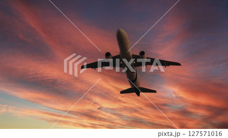 Airplane in the sky. Airplane in flight at sunset or evening sky. Commercial airliner silhouette in the colorful evening or night moon skies. Aircraft symbol of travel adventure global connectivity. 127571016