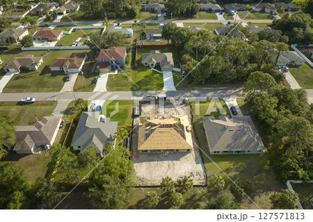 Aerial view of suburban private house wit wooden roof frame under construction in Florida quiet rural area Aerial view of suburban private house wit wooden roof frame under construction in Florida quiet rural area 127571813