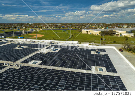 Aerial view of solar power plant with blue photovoltaic panels mounted on industrial building roof for producing green ecological electricity. Production of sustainable energy concept 127571825