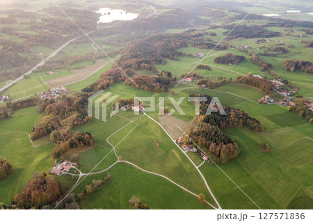 Aerial view of small scattered farm houses with red tiled roofs among green farming fields and distant forest in summer. 127571836
