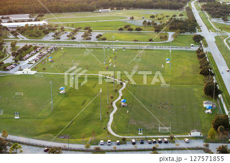 Aerial view of public sports park with children engaged in football game on grass stadium at sunset. Active way of life concept Aerial view of public sports park with children engaged in football game on grass stadium at sunset. Active way of life concept 127571855