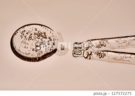 The texture of the serum and the pipette on a beige background. 127572275