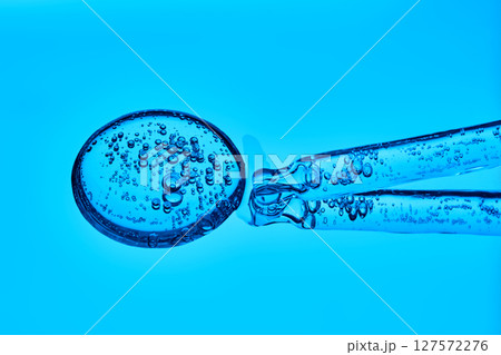 The texture of serum with spicules in a dropper on a blue background. The texture of serum with spicules in a dropper on a blue background. 127572276