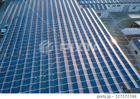 Aerial view of blue photovoltaic solar panels mounted on industrial building roof for producing green ecological electricity. Production of sustainable energy concept Aerial view of blue photovoltaic solar panels mounted on industrial building roof for producing green ecological electricity. Production of sustainable energy concept 127572398