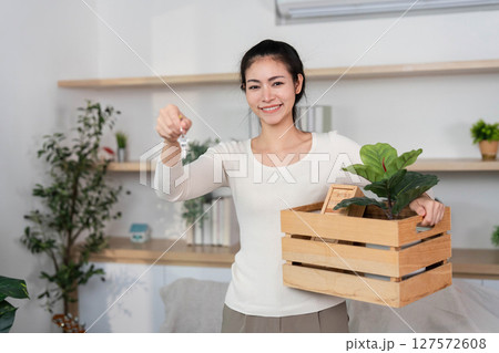 Moving and Gardening. Woman holding plant in a crate while moving into new home. 127572608