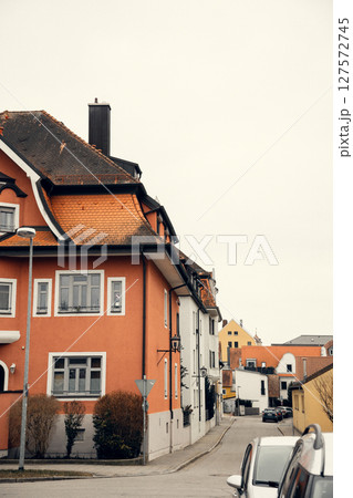 A European street lined with historic buildings featuring red-tiled roofs and vibrant facades. The A European street lined with historic buildings featuring red-tiled roofs and vibrant facades. The 127572745