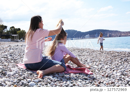 mother with twins daughters on beach 127572969