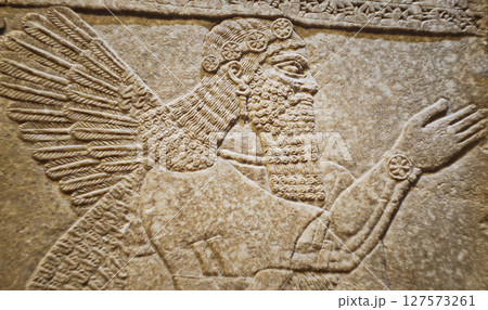 Close-up view on Winged Figure. Architectural Fragment Of Panel From Northwest Palace Of Ashurnasirpal Ii By Neo Assyrian Period. Depicted Is Winged Human Divine Spirit, Protective Spirit. High Priest 127573261
