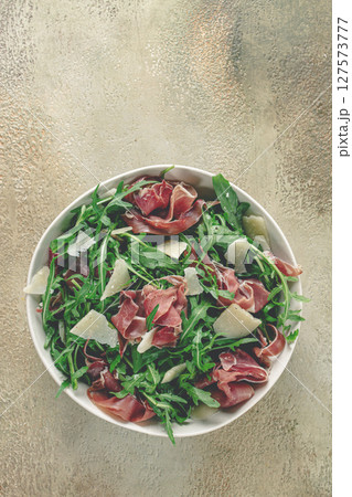 Fresh arugula salad with prosciutto and grated parmesan cheese, on a plate, homemade, no people, Fresh arugula salad with prosciutto and grated parmesan cheese, on a plate, homemade, no people, 127573777