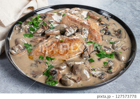 chicken in cream sauce with mushrooms, on a black plate, no people chicken in cream sauce with mushrooms, on a black plate, no people 127573778