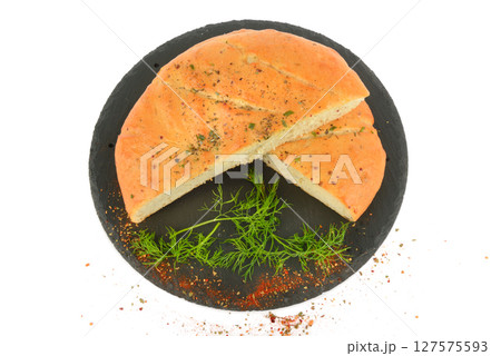 Freshly baked flat small bread with cheese, garlic and spices on black tray isolated on white. 127575593
