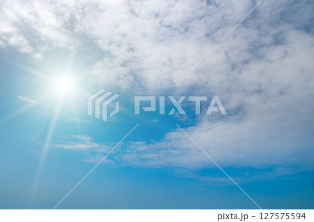 Bright sun and white clouds in clear blue sky 127575594