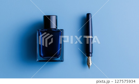 A blue ink bottle and a fountain pen placed neatly on a blue surface 127575934