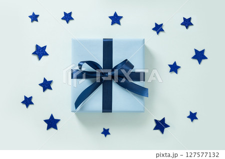 Blue gift box and blue stars on blue background. Greeting card. View from above. Flat lay. American Independence Day. Happy Labor Day Blue gift box and blue stars on blue background. Greeting card. View from above. Flat lay. American Independence Day. Happy Labor Day 127577132