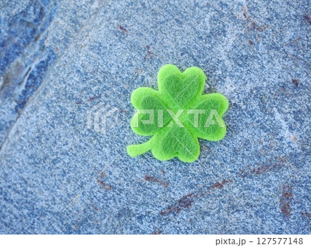 A green shamrock is sitting on a rock 127577148