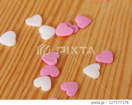 A pile of pink and white heart shaped candies on a wooden table A pile of pink and white heart shaped candies on a wooden table 127577176