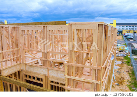 Workers assemble wooden frame for new building, suburban location construction process materials used. 127580102