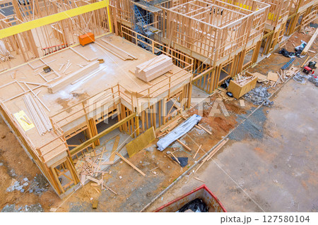 Construction workers are assembling wooden frames at site with materials scattered around on works day. Construction workers are assembling wooden frames at site with materials scattered around on works day. 127580104