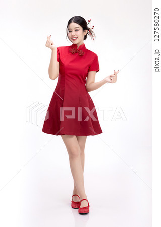 Full body portrait of joyful beauty Asian woman in red Cheongsam Chinese traditional dress celebrating and making heart shape hand sign isolated on white background. Full body portrait of joyful beauty Asian woman in red Cheongsam Chinese traditional dress celebrating and making heart shape hand sign isolated on white background. 127580270