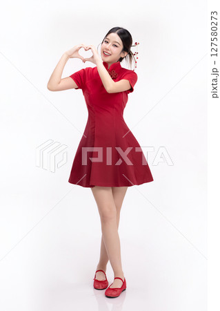 Full body portrait of joyful beauty Asian woman in red Cheongsam Chinese traditional dress celebrating and making heart shape hand sign isolated on white background. 127580273