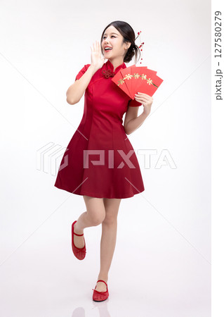 Portrait of joyful beauty Asian woman in red Cheongsam Chinese traditional dress celebrating with lucky red envelopes on Chinese New Year festival isolated on white background. Portrait of joyful beauty Asian woman in red Cheongsam Chinese traditional dress celebrating with lucky red envelopes on Chinese New Year festival isolated on white background. 127580279