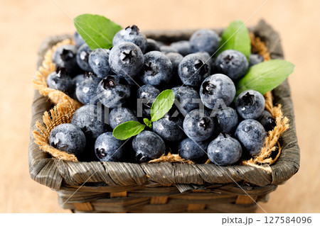 Ripe blueberries in wicker basket on wooden table. 127584096