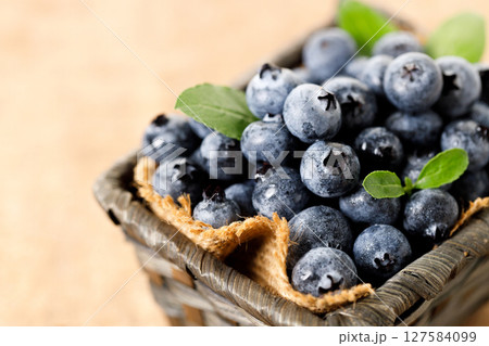 Ripe blueberries in wicker basket on wooden table. Ripe blueberries in wicker basket on wooden table. 127584099