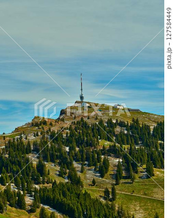 Mountaintop landscape features communication tower surrounded by lush green forest under a clear sky Mountaintop landscape features communication tower surrounded by lush green forest under a clear sky 127584449