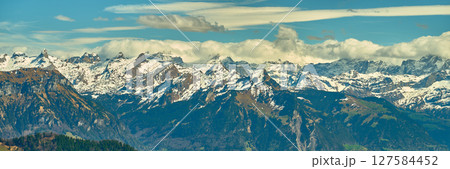 Majestic snow-capped mountains under a blue sky with drifting clouds in the Swiss Alps during midday Majestic snow-capped mountains under a blue sky with drifting clouds in the Swiss Alps during midday 127584452