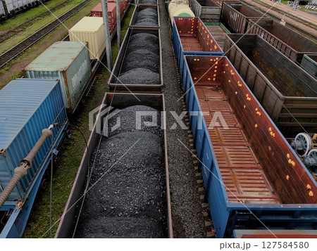 train yard filled with freight cars and cargo in an industrial setting during daylight hours. 127584580