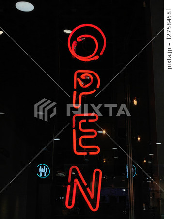 bright red neon sign indicating open status for a store featuring evening hours. closeup. 127584581