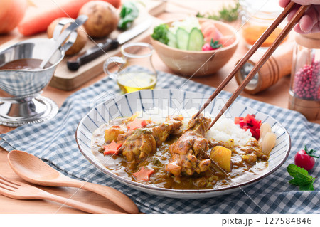 湯気立つ手作り手羽元カレーと彩り野菜の食卓 127584846