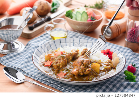湯気立つ手作り手羽元カレーと彩り野菜の食卓 127584847