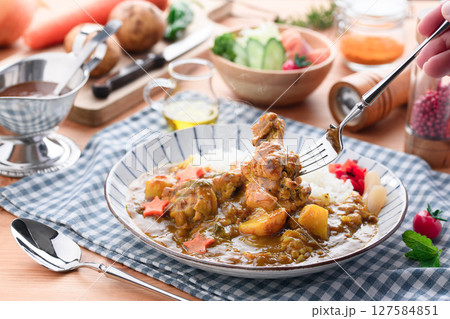 湯気立つ手作り手羽元カレーと彩り野菜の食卓 127584851
