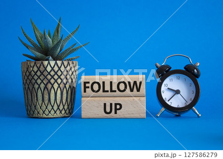 Follow up symbol. Concept word Follow up on wooden blocks. Beautiful blue background with alarm clock and succulent plant. Business and Follow up concept. Copy space 127586279