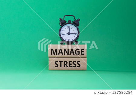 Manage stress symbol. Concept word Manage stress on wooden blocks. Beautiful green background with alarm clock. Business and Manage stress concept. Copy space 127586284