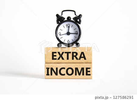 Extra Income symbol. Concept words Extra Income on wooden blocks. Beautiful white background with alarm clock. Business and Extra Income concept. Copy space. Extra Income symbol. Concept words Extra Income on wooden blocks. Beautiful white background with alarm clock. Business and Extra Income concept. Copy space. 127586291