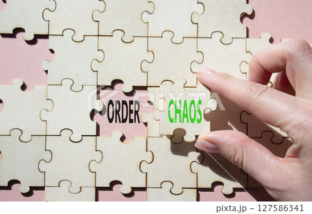 Chaos or Order symbol. Concept word Chaos or Order on wooden puzzle. Businessman hand. Beautiful pink background. Business and Chaos or Order concept. Copy space 127586341
