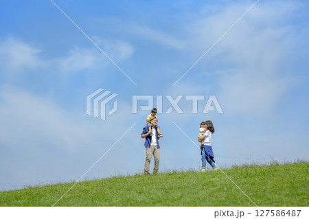 公園の丘で遊ぶ4人家族 127586487