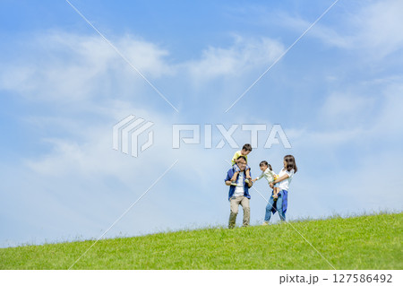 公園の丘で遊ぶ4人家族 127586492
