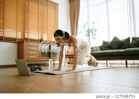 Young Asian woman doing sport exercises indoor. Beautiful girl workout at home Young Asian woman doing sport exercises indoor. Beautiful girl workout at home 127586751