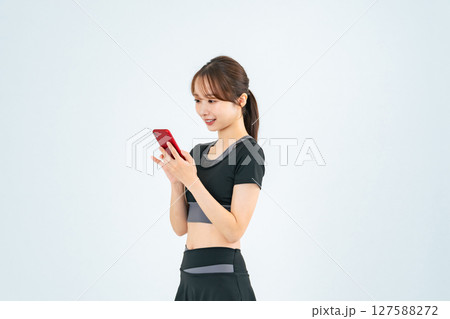 スポーツウェアを着てスマホを見る女性 スポーツウェアを着てスマホを見る女性 127588272