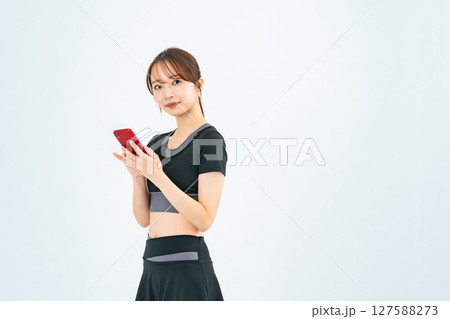 スポーツウェアを着てスマホを見る女性 スポーツウェアを着てスマホを見る女性 127588273