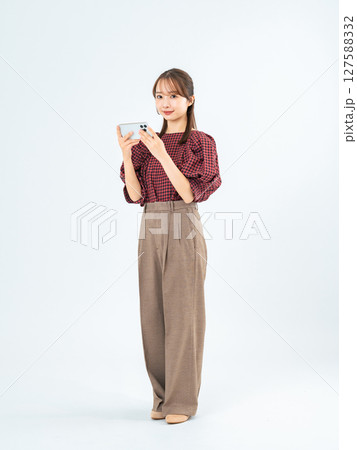 スマホを見るカジュアルウェアの女性の全身写真 127588332